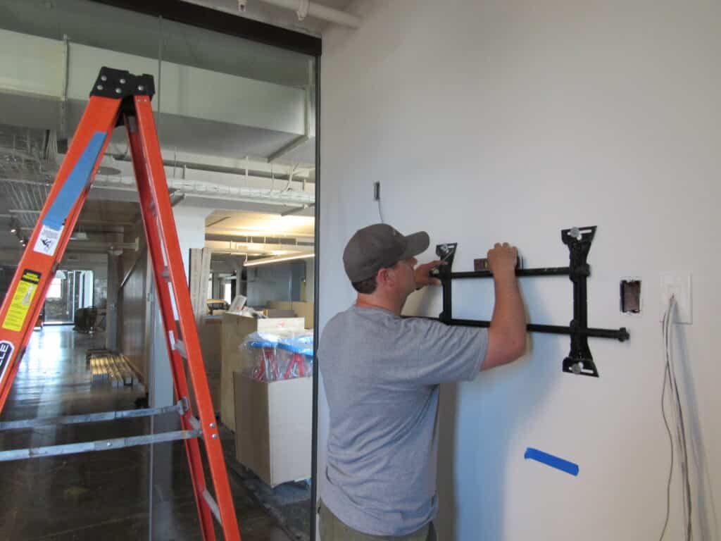 EDC employee installing a wall mount for AV equipment