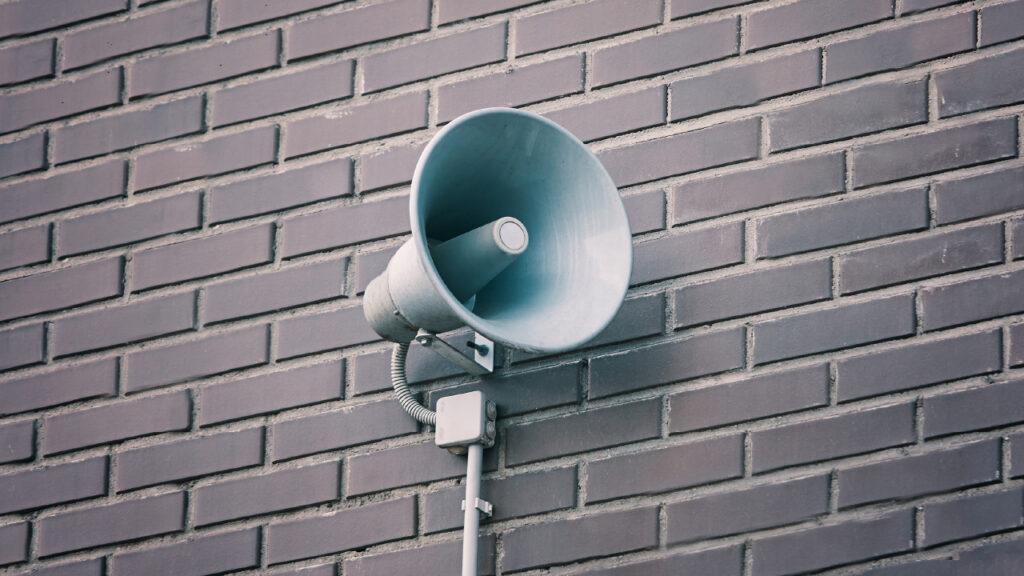 A photo of an emergency siren attached to a brick wall