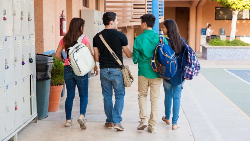 High school students listen to an announcement over the intercom systems as they walk on their way to class.