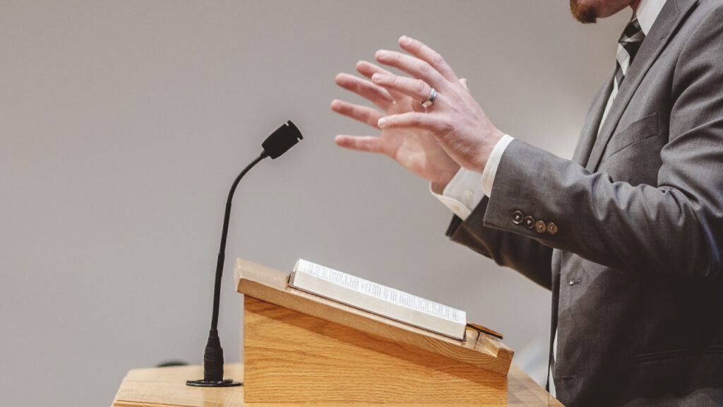 man speaking at a podium at a church