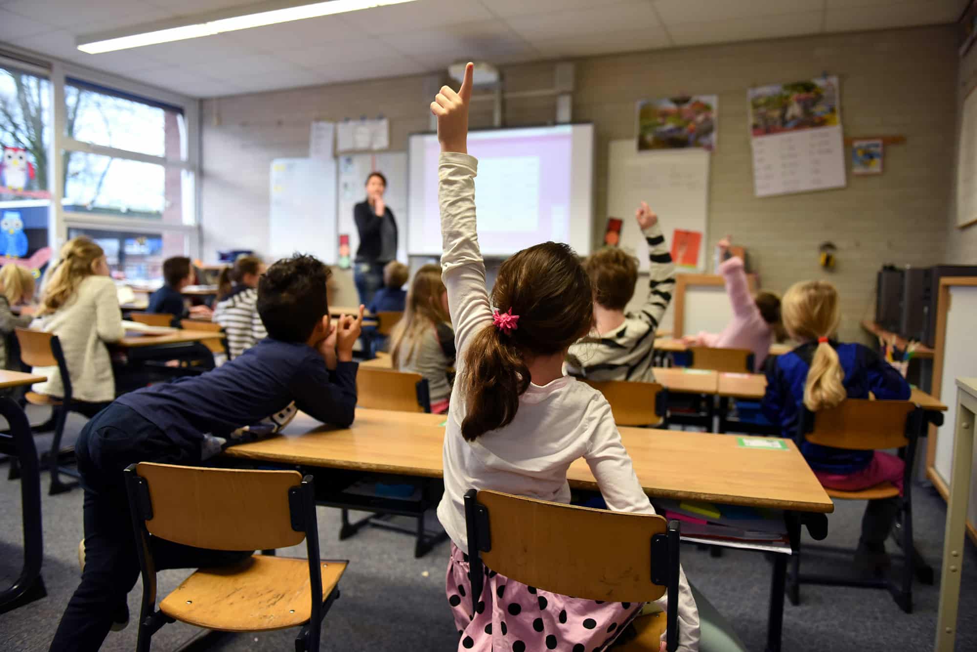 A classroom with a student raising her hand
