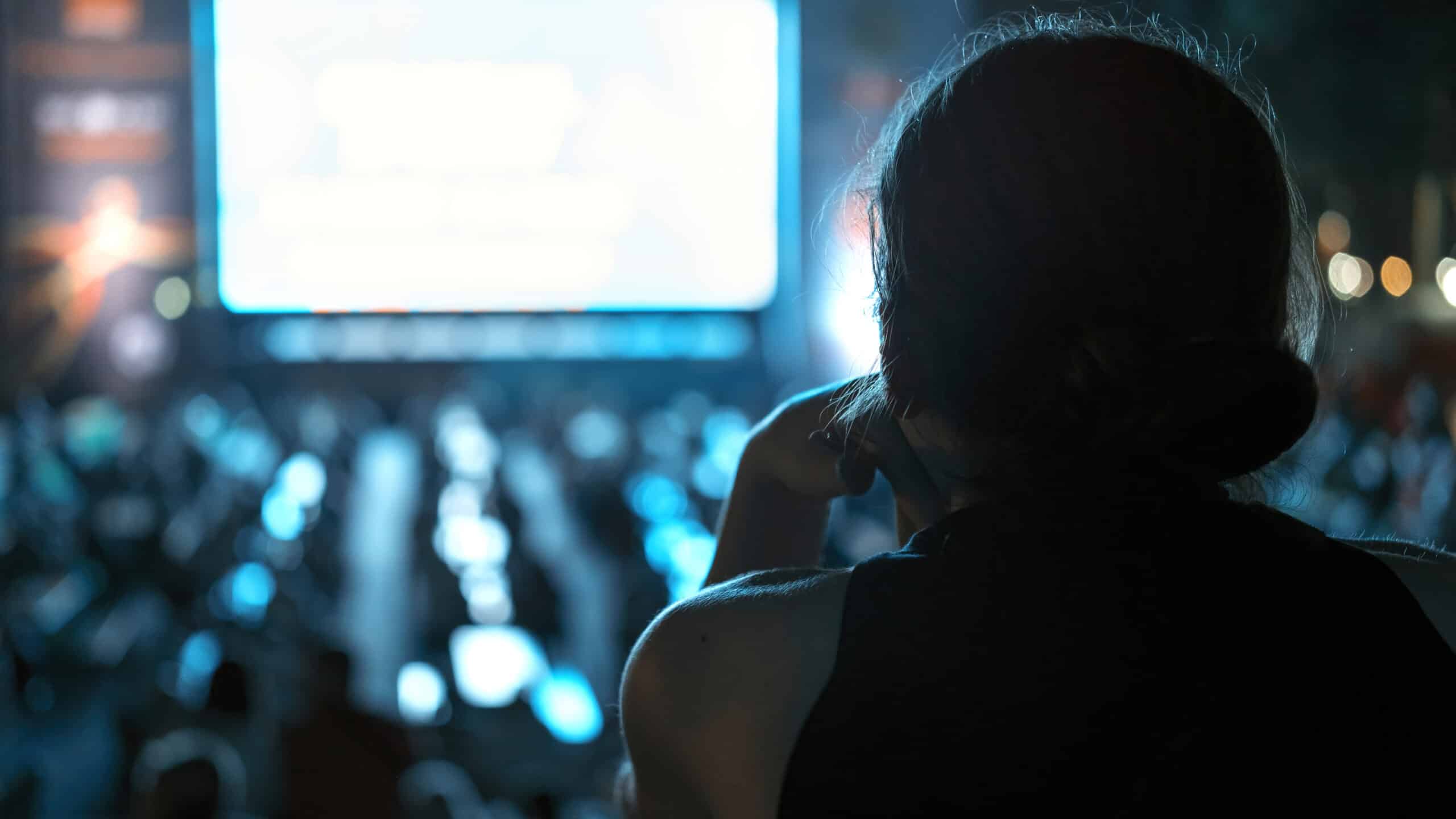 Woman watching football in a public place at night